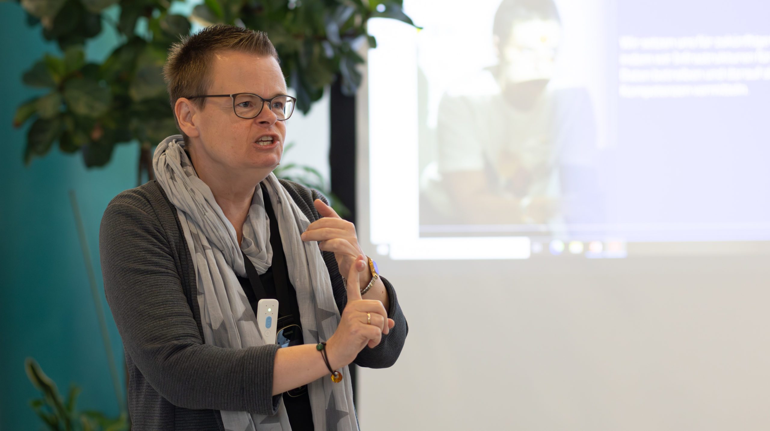 Vordergrund: Dr. Jasmin Schmitz (stellv. Leiterin des Programmbereichs Open Science und Leiterung der Abteilung Publikationsberatung) hält einen Vortrag, Hintergrund: Leinwand mit Präsentation